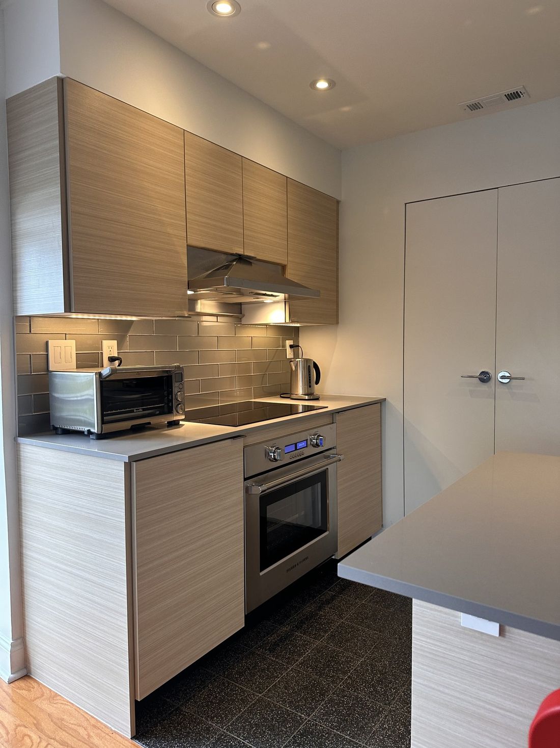 Flush, frameless white closet doors rise to the soffit line beside the new range wall.