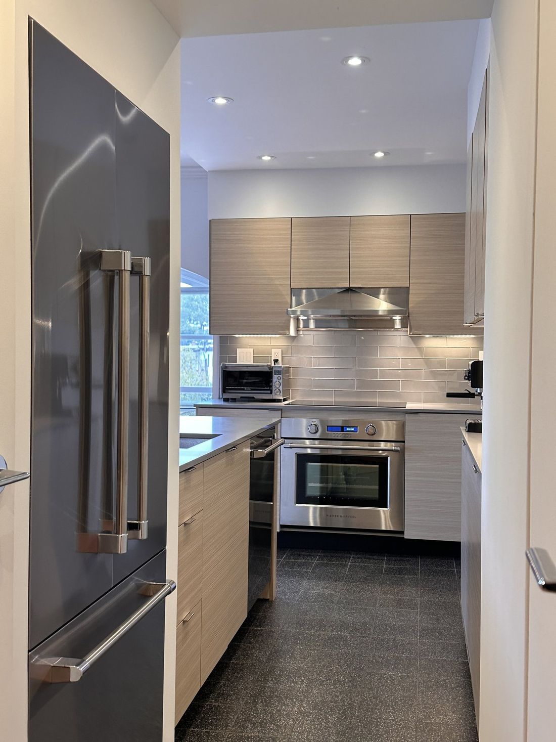 The refrigerator sits in a recessed alcove with both French doors able to open, and the kitchen is visible beyond.